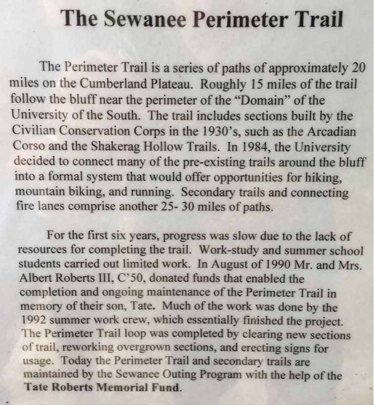 Alt text: A historical plaque detailing the Sewanee Perimeter Trail, describing its development, including its length, origins, and contributions from the Civilian Conservation Corps and the Tate Roberts Memorial Fund. The text outlines the trail's purpose for hiking, mountain biking, and running, and mentions key figures in its establishment. perimeter TrIl mountain bike trail.