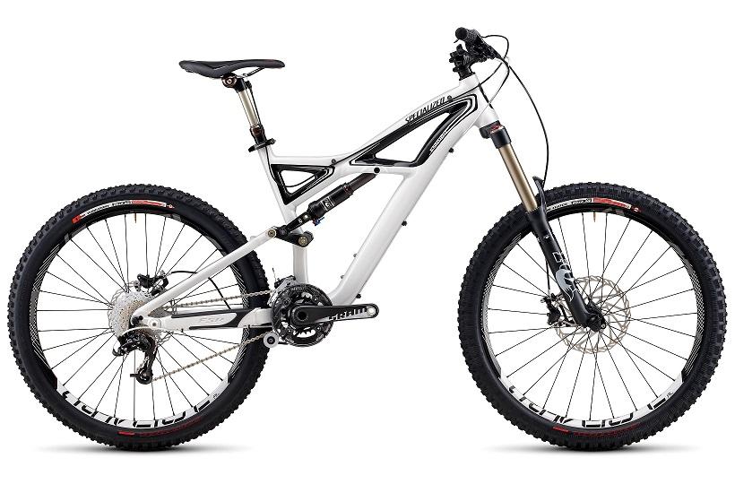 Specialized Enduro Expert: Mountain bike with a sleek white frame, featuring dual suspension, wide tires, and disc brakes, positioned on a plain background.