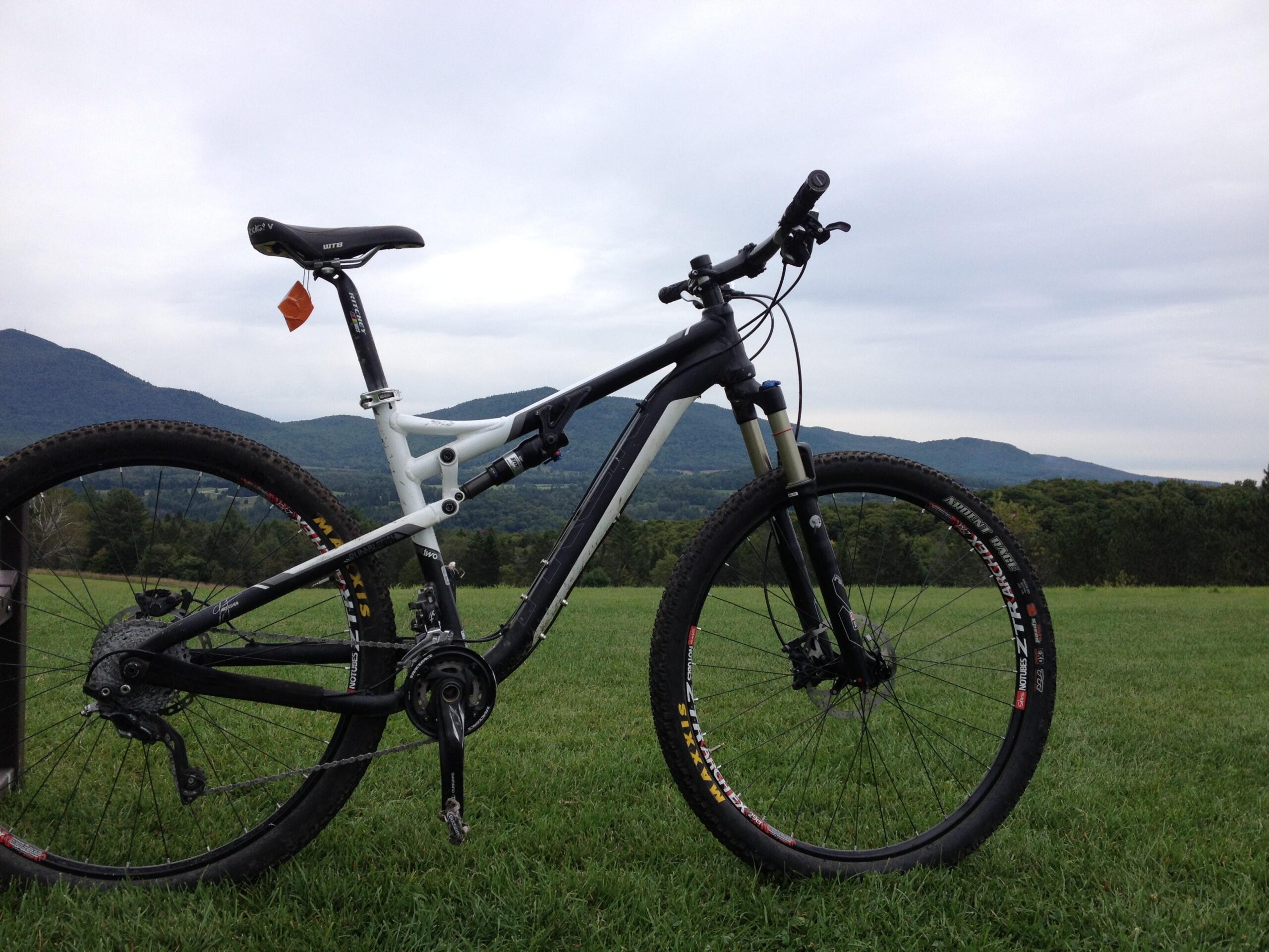 Trek Rumblefish II: Mountain bike positioned on green grass with a scenic mountain range in the background under a cloudy sky.