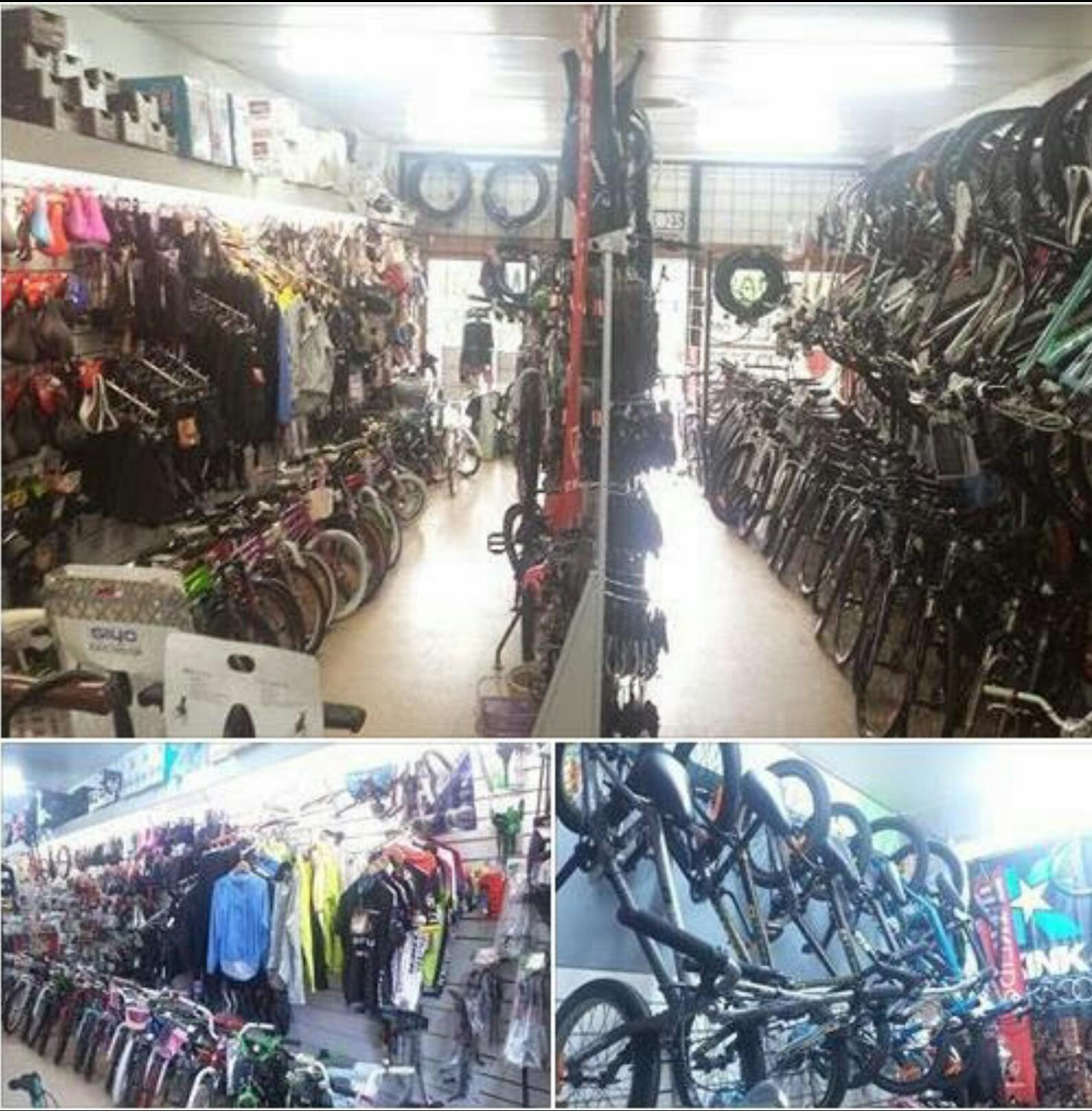 A busy bicycle shop interior filled with a variety of bicycles along the walls and racks, alongside bicycle accessories and clothing displayed on the shelves. The space is well-lit, showcasing different types of bikes and equipment for cycling enthusiasts.