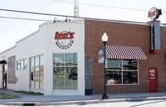 Exterior view of a brick building featuring a restaurant with large windows, a striped awning, and signage that includes the name of the establishment. The location is well-lit and situated on a street corner, highlighting its accessibility.