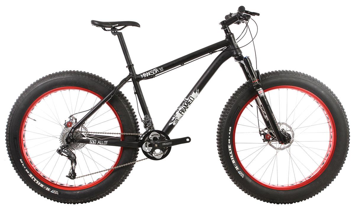 Framed Minnesota 3.0: A black mountain bike with wide tires featuring red rims. The bike has a sturdy frame, front suspension, and visible gear components, displaying a sleek design ideal for off-road riding. The model name "Minnesota 3.0" is prominently displayed on the frame.