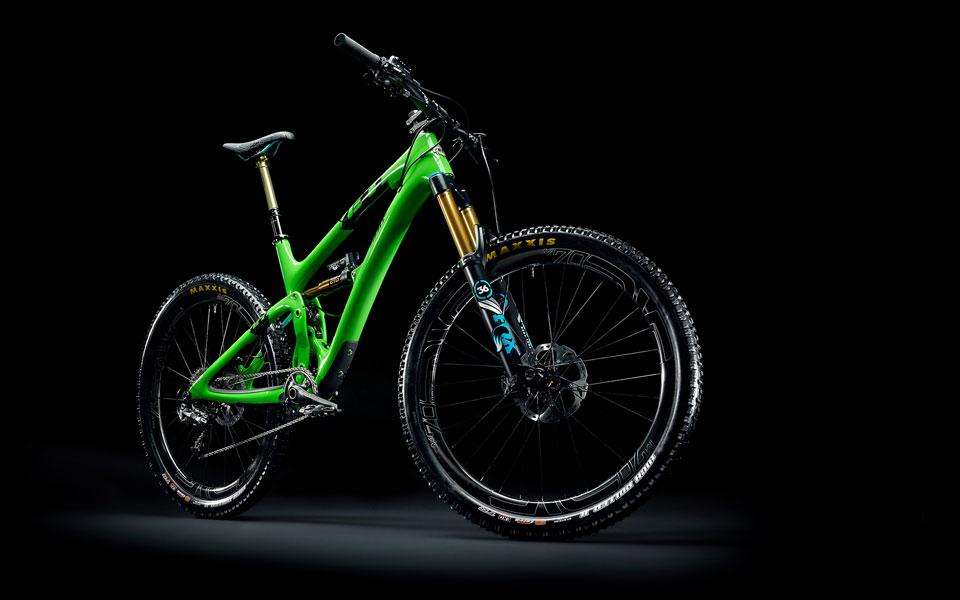 Yeti SB6: Mountain bike with a vibrant green frame, featuring a front suspension fork and rugged tires, displayed against a dark background.