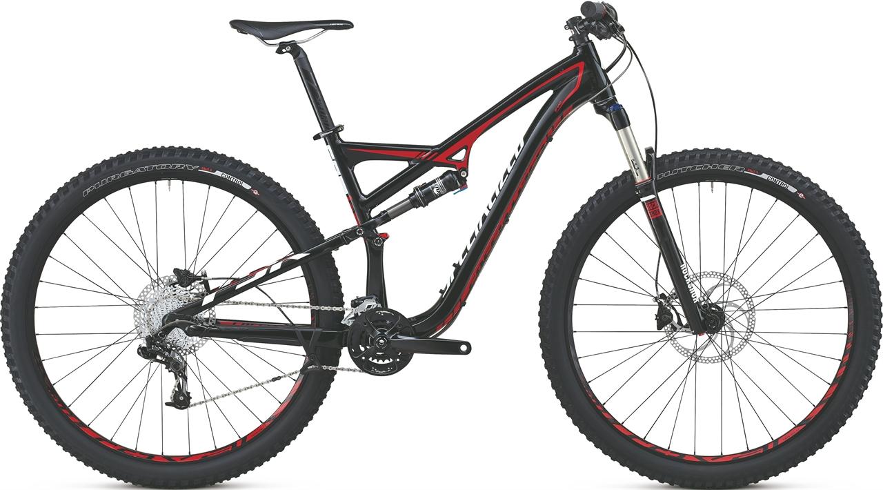 Specialized Camber EVO 29: A black and red mountain bike with a full suspension design, featuring wide tires and disc brakes. The bike's frame includes sleek curves and a modern aesthetic, suitable for off-road cycling.