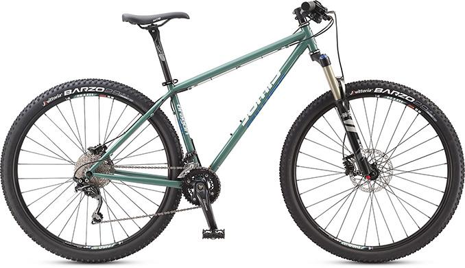 Jamis 2013 Dragon 29 Sport: A green mountain bike with a solid frame, front suspension, and knobby tires, featuring branding on the frame and wheels. The bike is positioned against a white background, showcasing its design and components.
