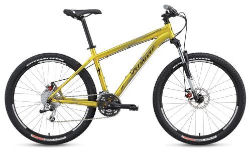 Specialized Rockhopper Comp Disc: Mountain bike with a bright yellow frame, front suspension, and wide tires, positioned on a white background.
