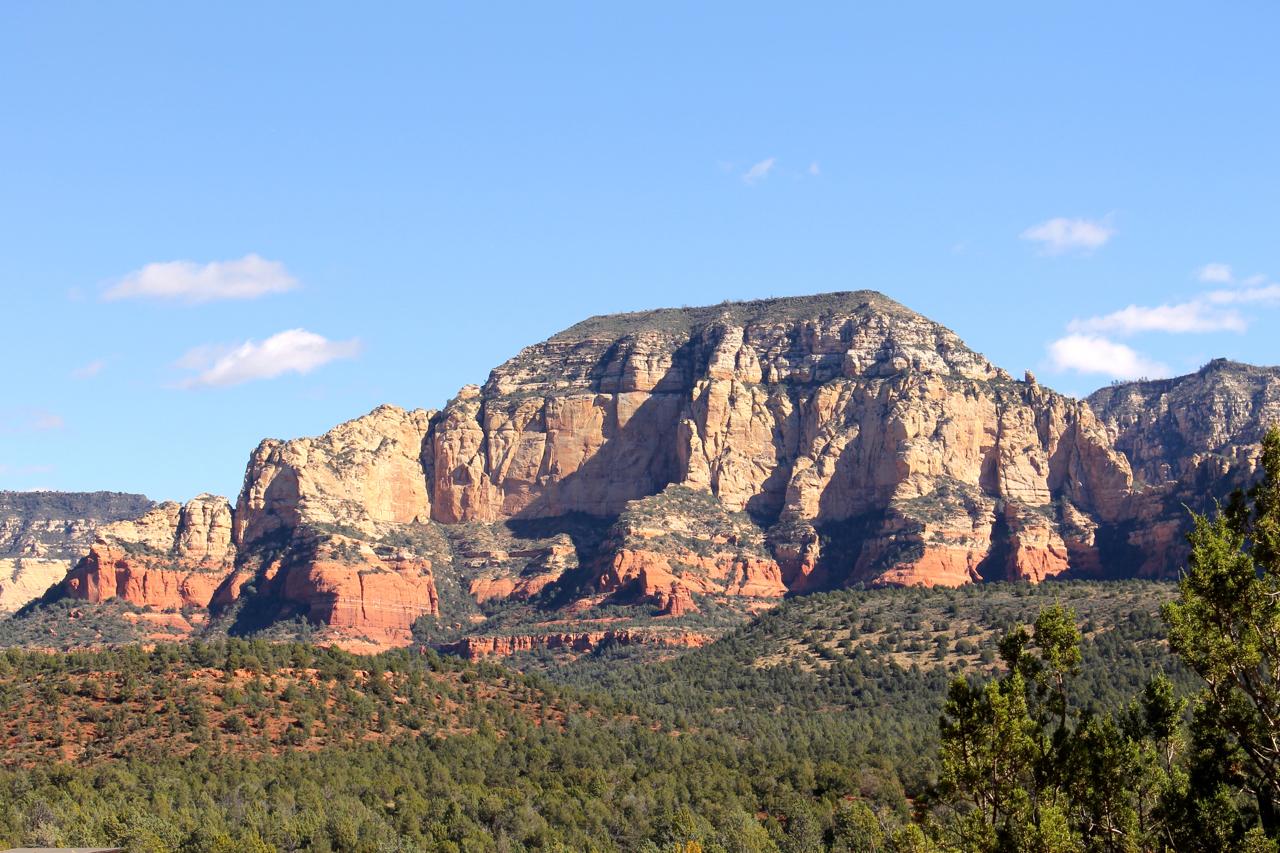 A scenic view of large rock formations and cliffs against a clear blue sky, surrounded by green vegetation and desert landscape, showcasing the natural beauty of a mountainous region. Upper Dry Creek Area Trails mountain bike trail.