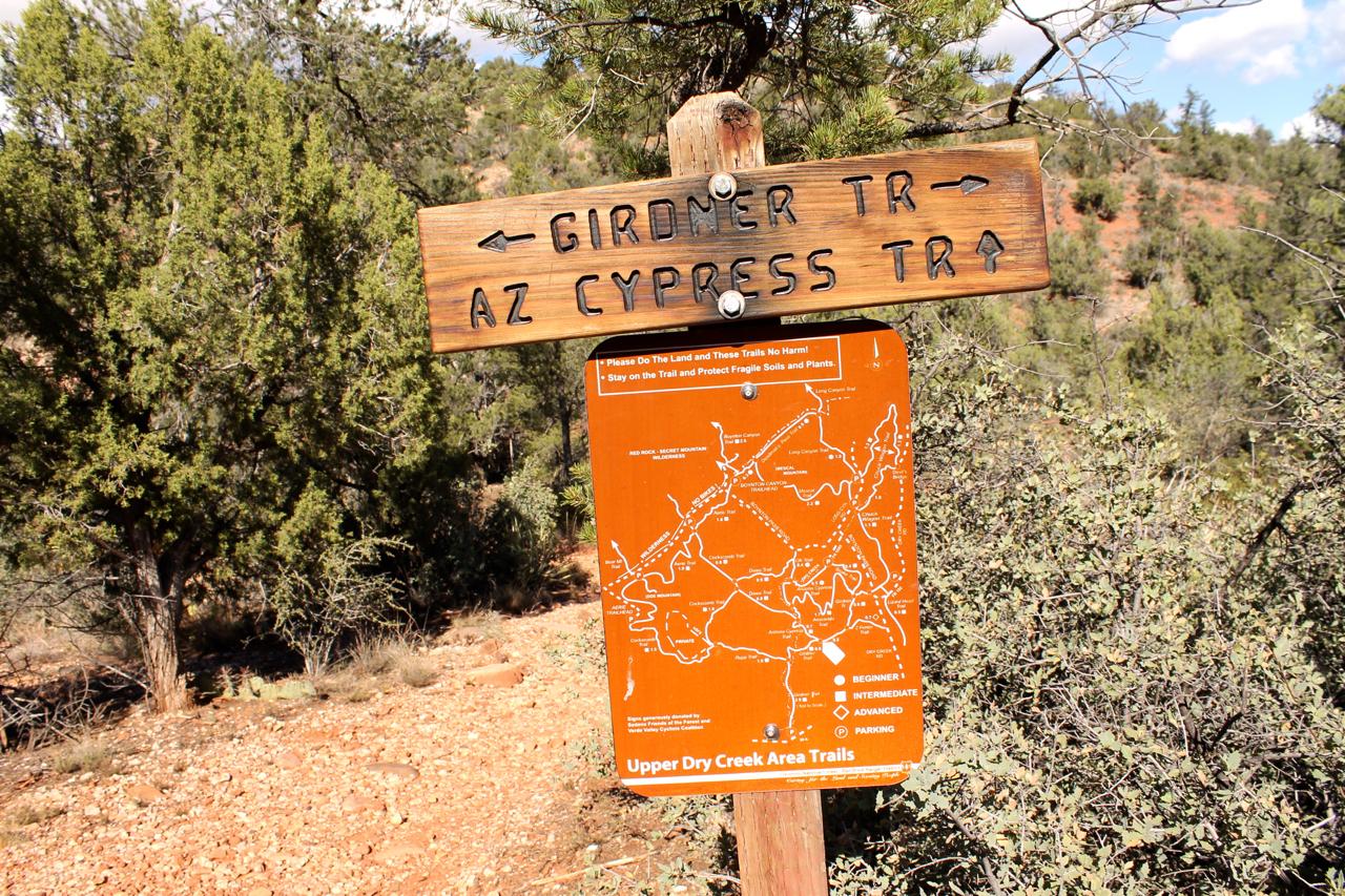 A wooden trail sign pointing to "Girder Trail" and "AZ Cypress Trail," accompanied by a map indicating various trails including beginner, intermediate, and advanced options in the Upper Dry Creek Area, with a background of green shrubs and trees. Upper Dry Creek Area Trails mountain bike trail.