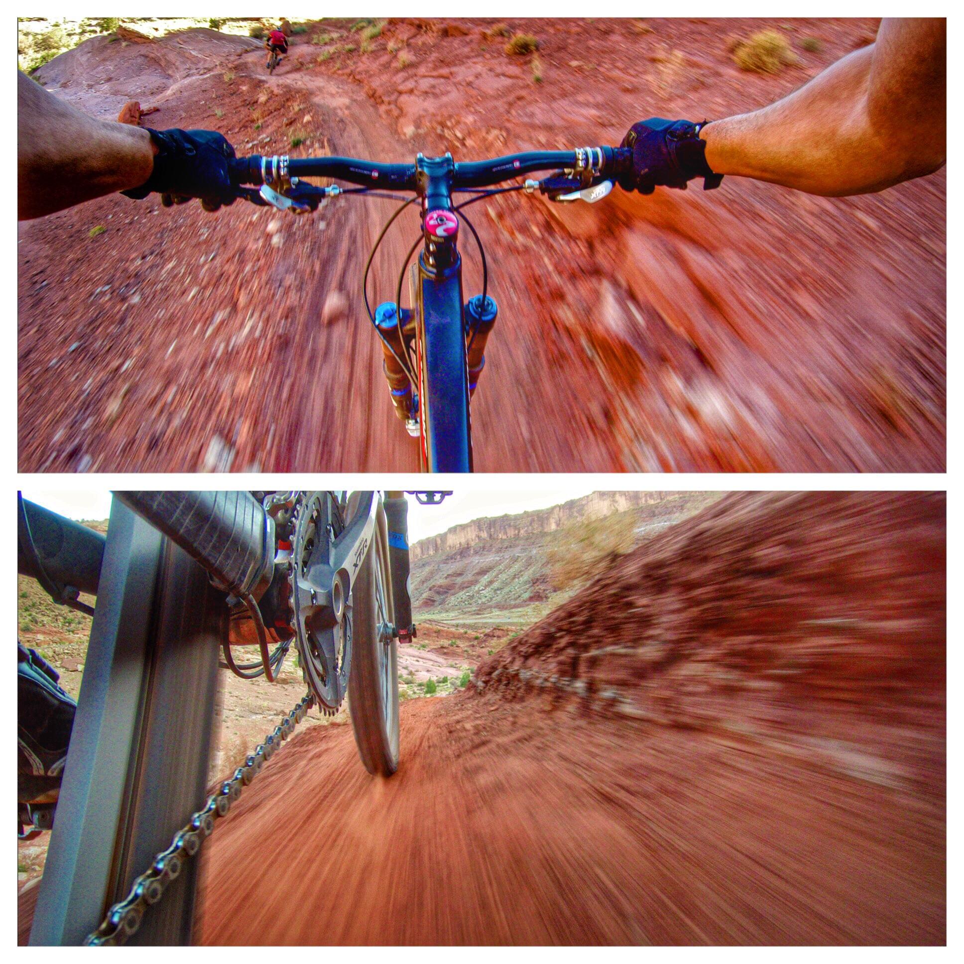 Alt text: A split image showing a mountain biker's view while riding on a dusty, red dirt trail. The top half captures the handlebars and a distant rider, while the bottom half focuses on the bike's gearing and rear wheel, showcasing the speed and terrain. Moab Brand Trails mountain bike trail.