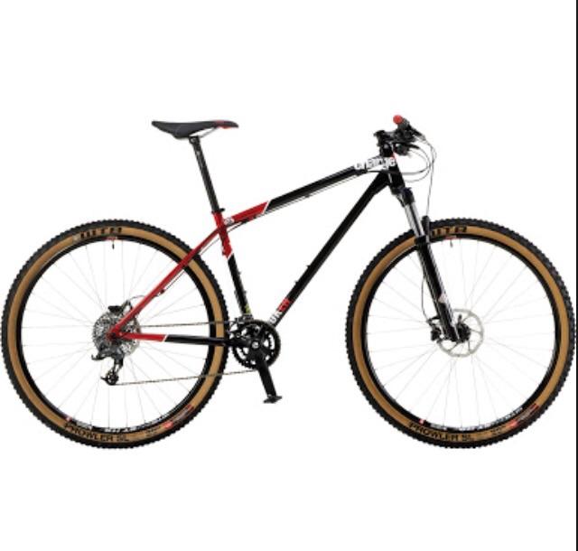 Charge Cooker 4: A black and red mountain bike with wide, knobby tires and a lightweight frame, featuring a front suspension fork and dual disc brakes, positioned against a plain white background.