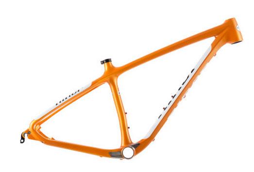 Niner Air 9: A brightly colored orange bicycle frame with a sleek, modern design, featuring prominent curves and a minimalist structure. The frame is shown from a side angle, highlighting its lightweight and aerodynamic shape, with a visible bottom bracket area and attachment points for components.
