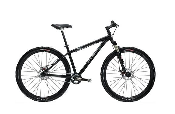 A black mountain bike with wide tires and a sturdy frame, featuring suspension forks, disc brakes, and a simple gear setup. The bike is displayed against a plain white background.