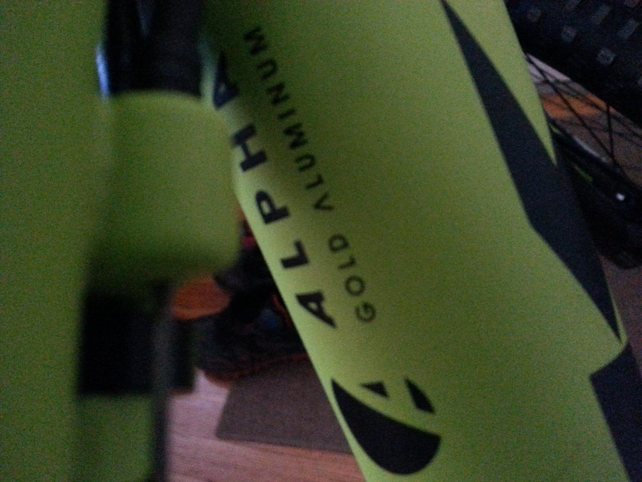 Trek Marlin 7: Close-up image of a bicycle frame in bright green featuring the text "ALPHA" and "GOLD ALUMINUM." The image captures part of the frame design, showcasing a sleek, modern look with a black accent.