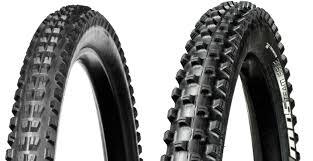 Bontrager G3 Team issue: Two bicycle tires side by side, showcasing different tread patterns. The tire on the left features a smooth surface, suitable for road use, while the tire on the right displays an aggressive tread design, ideal for off-road terrain.