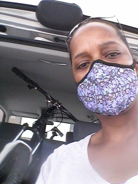 Jamis 2013 Dragon 29 Sport: A person wearing a patterned mask is taking a selfie in a vehicle, with a bicycle visible in the background.