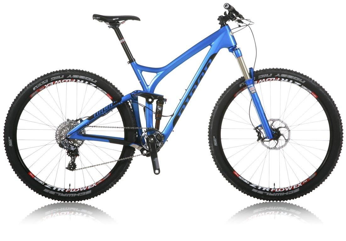 Niner R.I.P. 9 RDO: A blue mountain bike with a sleek design, featuring wide tires, a full suspension system, and a modern frame. The bike is shown at an angle, highlighting its components such as the handlebars, disc brakes, and gear system. The reflective surface beneath the bike adds a polished look.