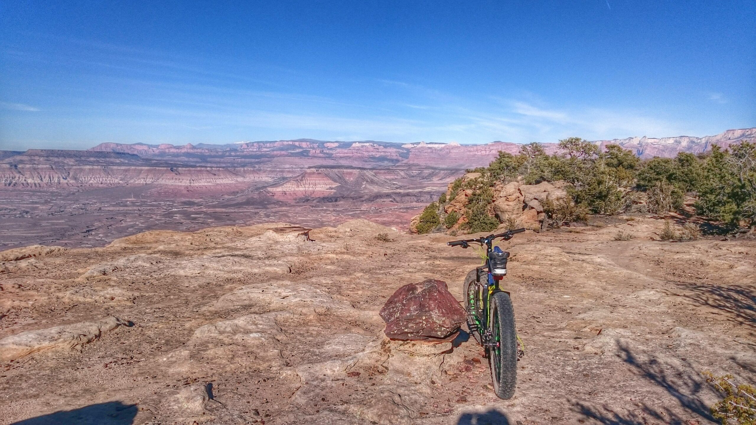 Mountain bike parked on rocky terrain with a vast desert landscape and blue skies in the background. Gooseberry Mesa mountain bike trail.