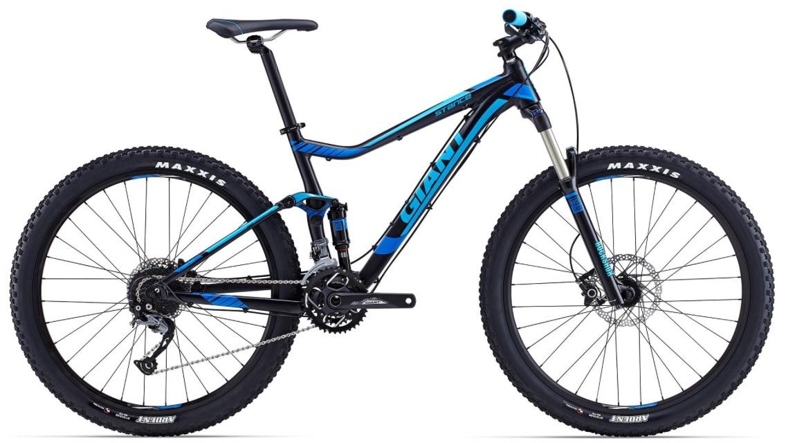 Giant Giant Stance 2: Alt text: A blue and black mountain bike displayed at an angle, featuring a lightweight frame, front suspension fork, wide tires labeled "Maxxis," and multiple gears, designed for off-road cycling.