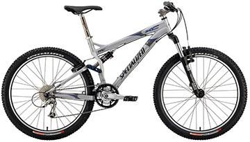 Specialized FSR XC Comp: A silver mountain bike with wide tires, front suspension, and a sleek frame design, positioned on a plain background.