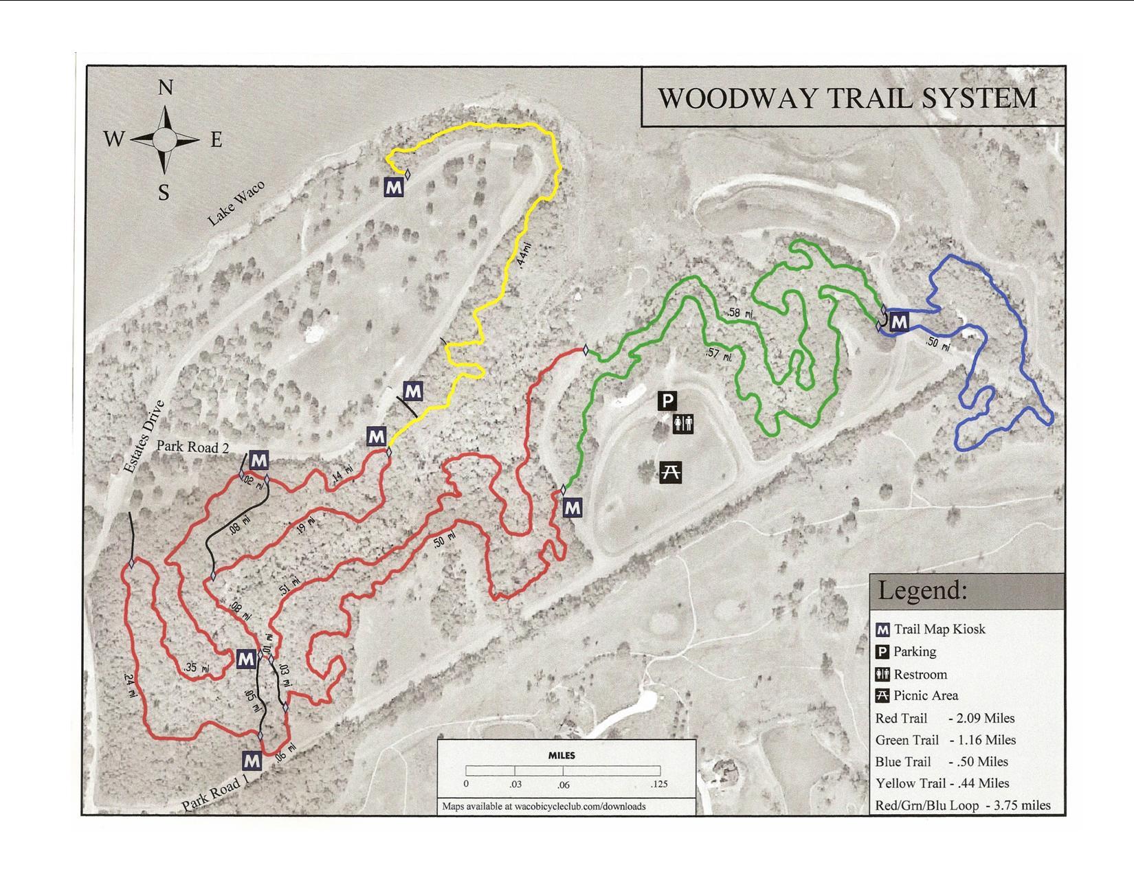 Map of the Woodway Trail System, showing various trails marked in different colors: red, green, blue, and yellow. Includes trail lengths and landmarks such as parking areas, restrooms, and picnic areas. The map also features a compass rose indicating orientation. Midway (Woodway) Park mountain bike trail.