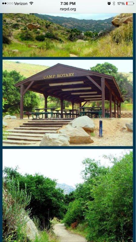 A scenic image featuring three sections: the top shows a green, hilly landscape; the middle depicts a wooden shelter with "CAMP ROTARY" signage and tables underneath; and the bottom presents a pathway through lush greenery. Corriganville Park Trails mountain bike trail.