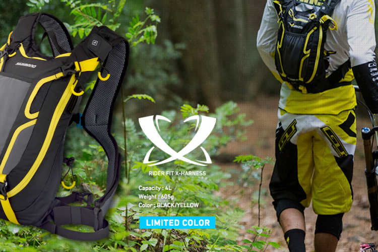 A black and yellow cycling backpack displayed among greenery, featuring details on its capacity of 4 liters and weight of 605 grams. The backpack is part of a limited color collection and is shown alongside a cyclist walking a bike in a forest setting.