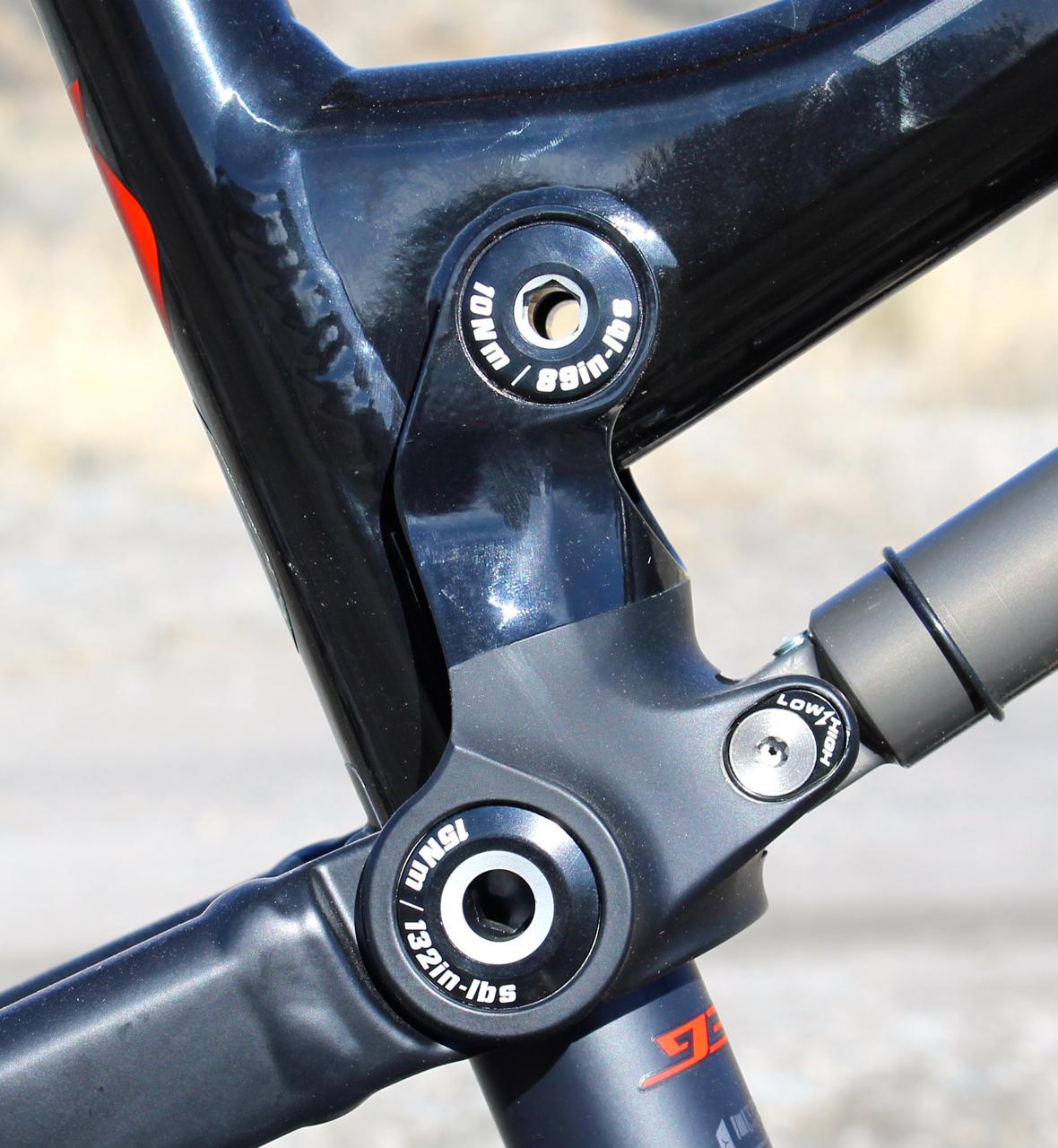 Scott Genius 930: A close-up image of a mountain bike's suspension linkage, featuring metal components and torque specifications labeled on the parts. The background is blurred, highlighting the intricate design and engineering of the suspension system.
