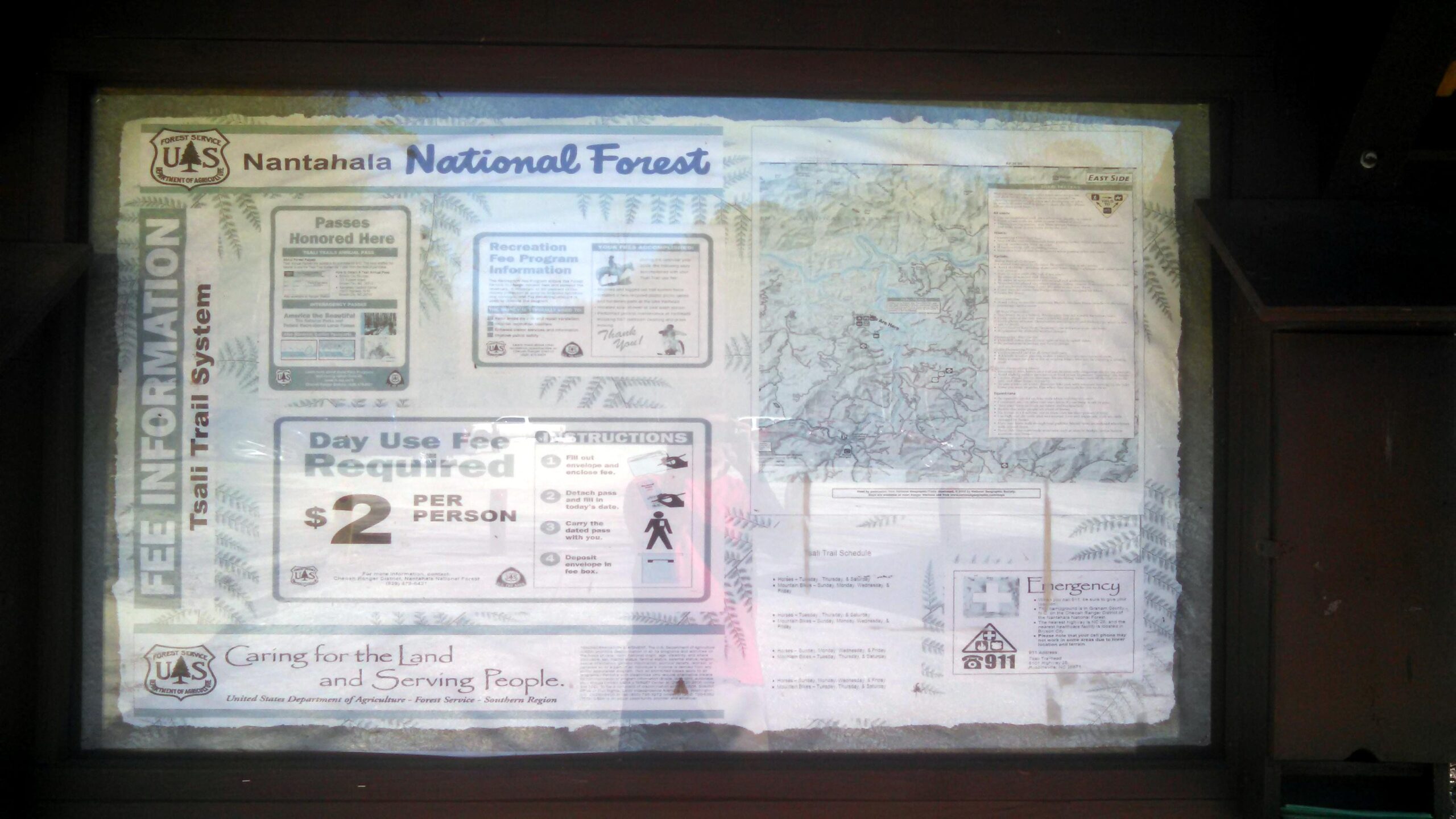 Information board for the Nantahala National Forest displaying recreational fee information, a trail map, instructions for the day use fee, and emergency contact details. Tsali Left Loop mountain bike trail.