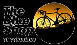 Silhouette of a bicycle against a circular orange and yellow gradient background, featuring the text "The Bike Shop of Columbus" in bold, contrasting typesetting.