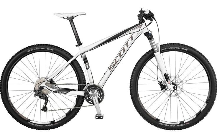 Scott Scale 29 Team: A high-quality mountain bike featuring a sleek white and black design, showcasing a lightweight frame, front suspension, knobby tires, and a multi-speed gear system. The bike is positioned on a plain background, highlighting its components and detailing.