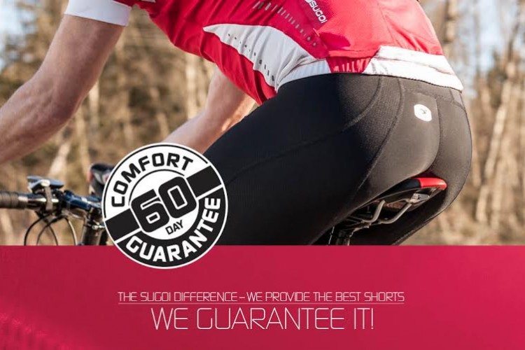 A cyclist wearing a red jersey and black padded shorts, positioned on a bicycle, with a forest background. The image features a text overlay promoting a 60-day comfort guarantee and highlights the quality of Sugoi shorts.