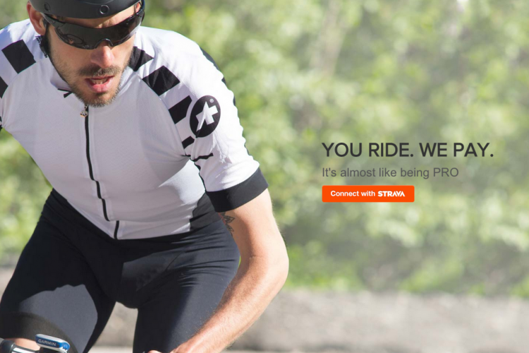 A cyclist in a white and black aerodynamic jersey and sunglasses is riding a bicycle with focused determination. The background features greenery, suggesting an outdoor setting. The text overlay reads, "YOU RIDE. WE PAY. It's almost like being PRO," with a button to "Connect with STRAVA."