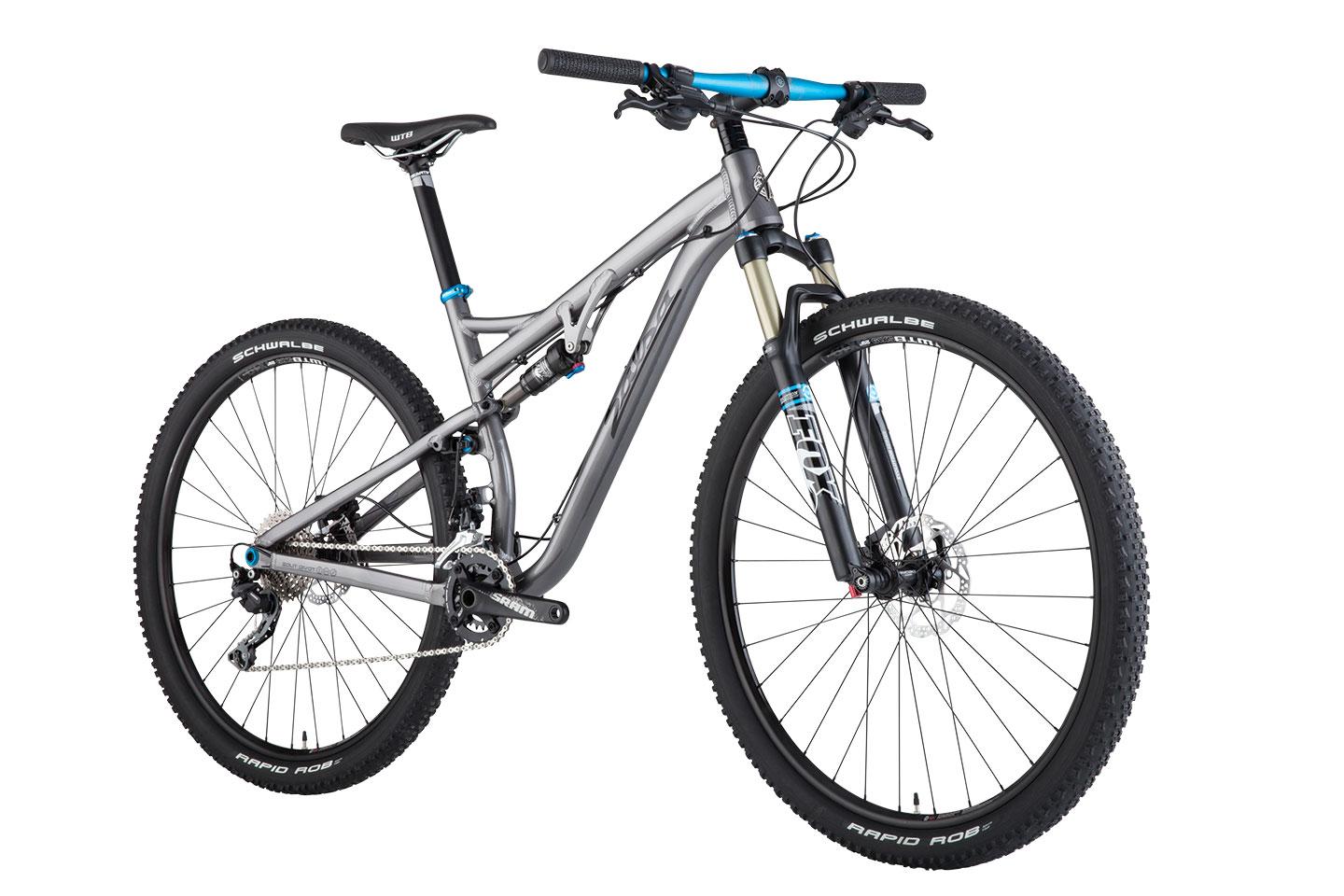 Salsa Spearfish: A silver mountain bike with blue accents, featuring a dual suspension setup, wide tires, and disc brakes. The bike is positioned upright, showcasing its frame, handlebars, and gears.