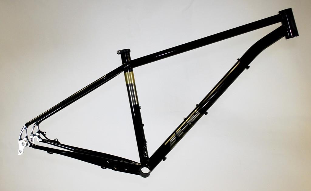 Zen TRAIL Frame: A black bicycle frame with gold accents, displayed against a neutral background. The frame features a sleek design, showing the connection points for the wheels, handlebars, and seat.