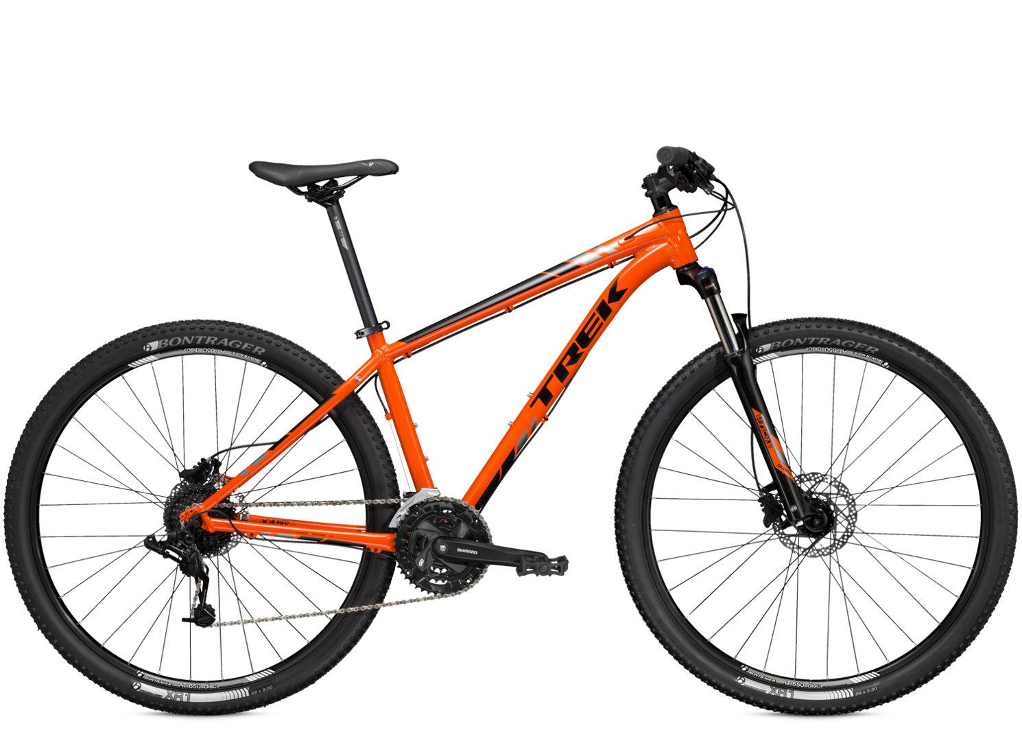 Trek x-caliber 6: Alt text: An orange mountain bike with a sleek design, featuring a black accent and Bontrager tires. The bike includes a front suspension fork, gear shifters on the handlebars, and a comfortable seat, positioned against a white background.