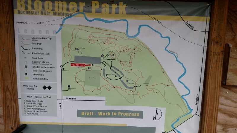 Map of Bloomer Park in Rochester Hills, Michigan, showing park pathways, mountain bike trails, restrooms, and a location marker indicating "You Are Here." The map is labeled with trail ratings and includes boundaries of the park. A note indicates that it is a draft in progress. Bloomer Park mountain bike trail.