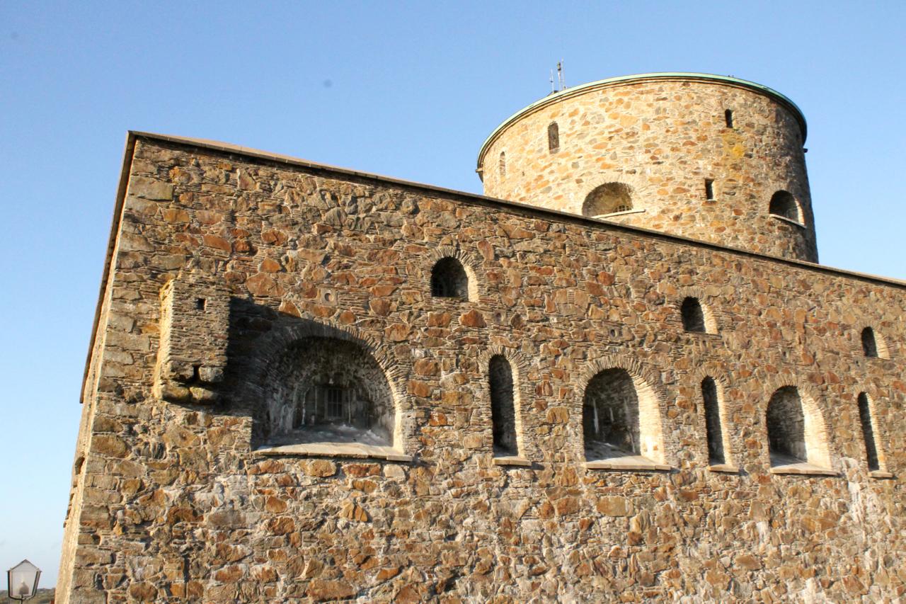 Stone tower with circular top and multiple arched windows against a clear blue sky. Marstrand Island Trail System mountain bike trail.