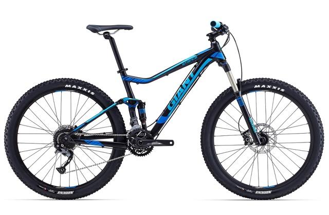 Giant Stance 27.5 2: A blue and black mountain bike with a modern frame design, featuring front suspension, wide tires, and disc brakes. The bike is positioned on a white background, highlighting its detailed components and contrasting colors.