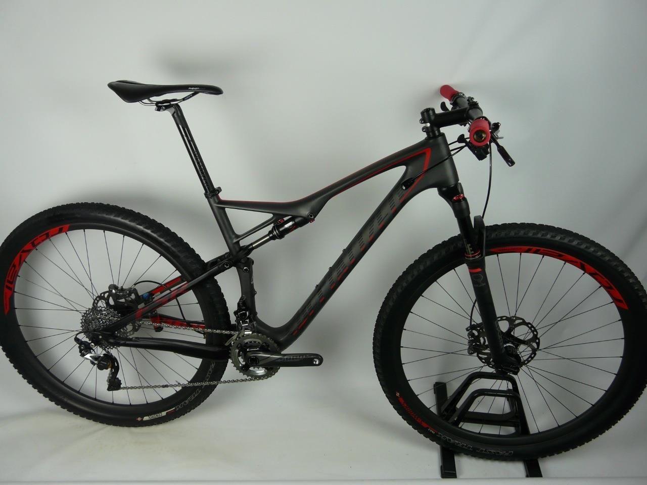 Specialized Epic Expert Carbon 29er: A sleek black and red mountain bike displayed on a stand, showcasing its lightweight frame, wide tires, and high-quality components. The bike is positioned against a neutral background, highlighting its modern design and features, including a suspension system and disc brakes.