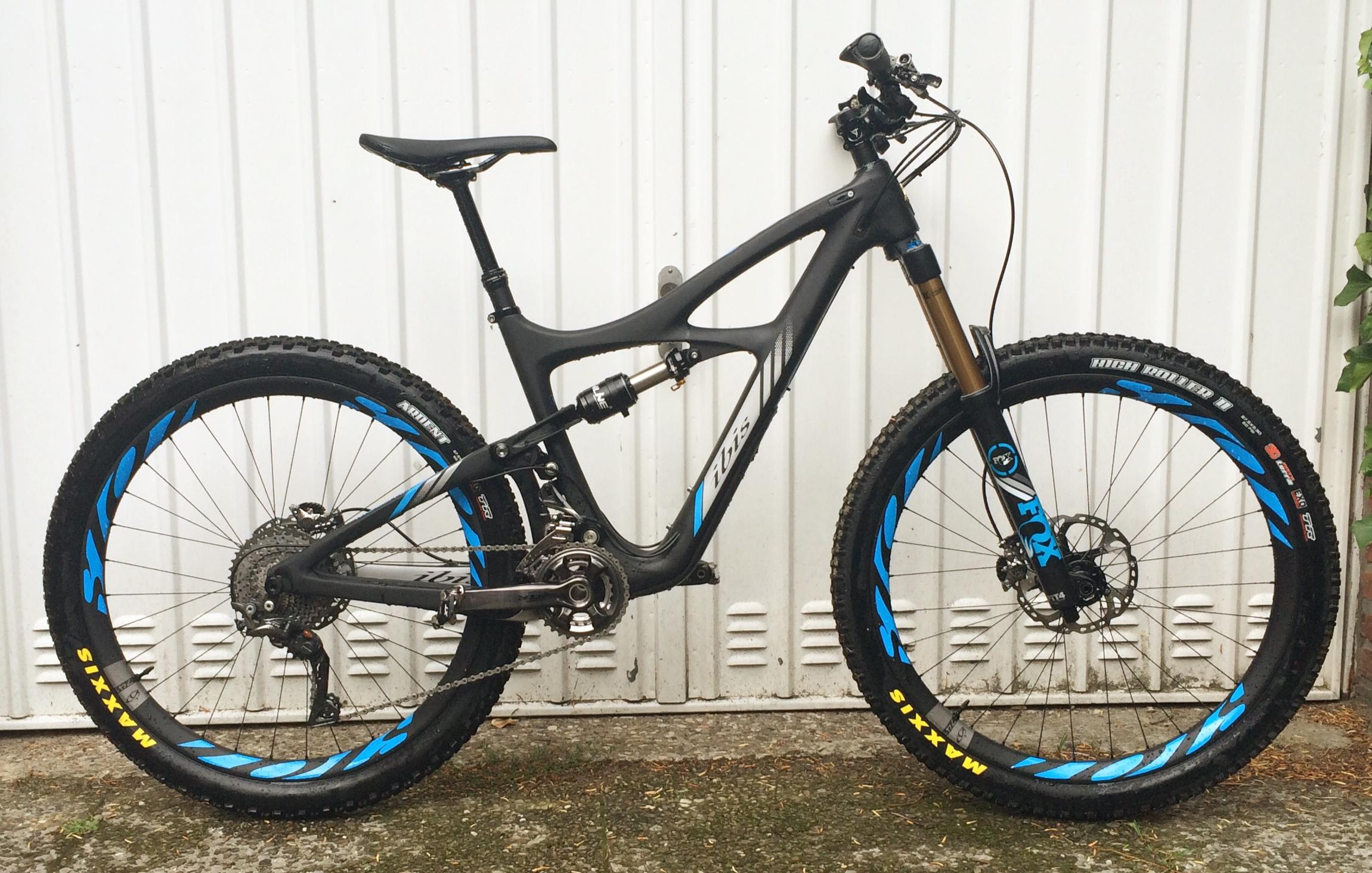 Ibis Mojo HD3: A side view of a black mountain bike with blue and yellow accents, featuring a suspension system, wide tires, and a modern design. The bike is positioned against a white background, highlighting its sleek frame and components.