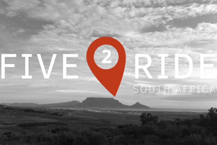 A scenic landscape featuring a mountainous backdrop with a cloudy sky, overlaid with the text "FIVE 2 RIDE" and "SOUTH AFRICA." A location pin symbol is incorporated into the design, emphasizing the theme of travel or adventure.
