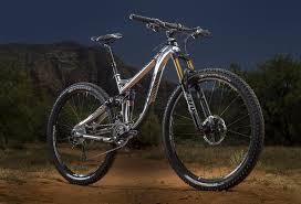 Trek Fuel EX 9: A high-quality mountain bike displayed on a dirt trail, showcasing its sleek frame and robust tires, set against a dramatic backdrop of mountains at dusk.