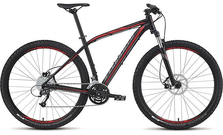 Specialized Rockhopper 29: A black and red mountain bike with wide tires, disc brakes, and a lightweight frame, positioned against a neutral background. The bike features a gear system and is designed for off-road cycling.