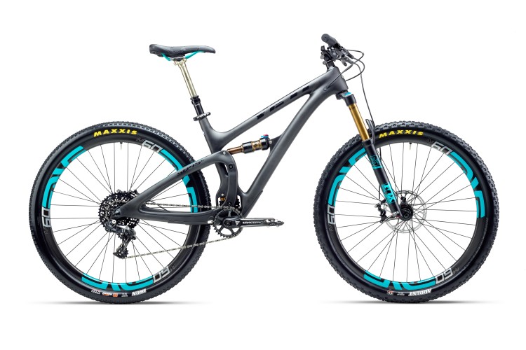 A sleek, modern mountain bike with a lightweight gray frame, wide black tires featuring turquoise accents, and high-quality components. The bike is positioned against a white background, showcasing its dual suspension system, prominent fork, and a single gear setup, highlighting its suitability for rugged trails.