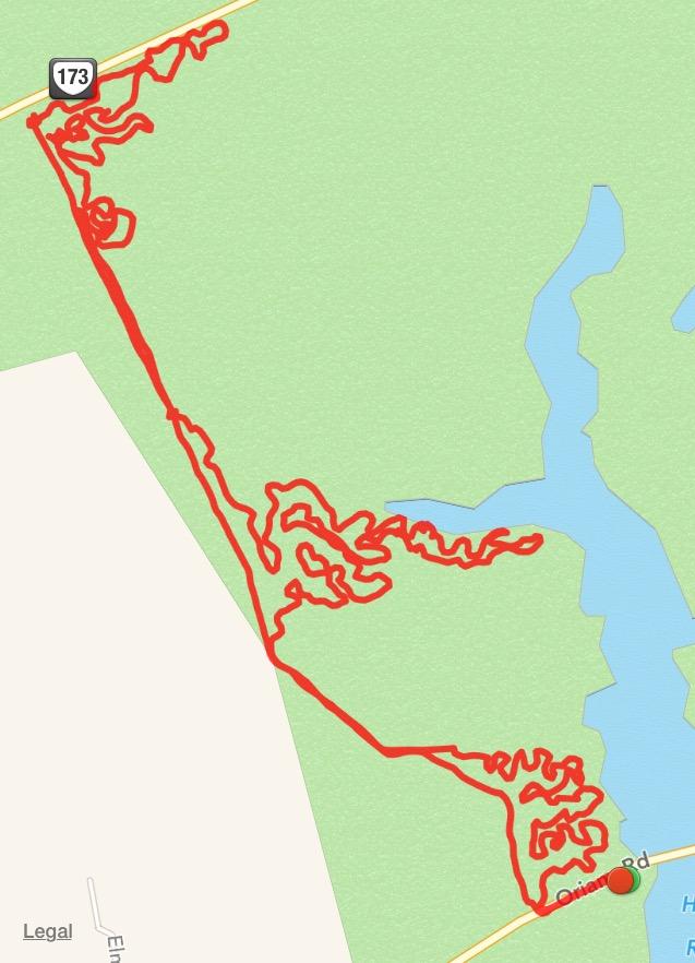 A map showing a path traced in red, highlighting a series of winding trails and roads within a green landscape, with a water body in the upper right corner. Key landmarks include a road labeled "173" and a location marked "Oivan Rd." Harwood's Mill mountain bike trail.