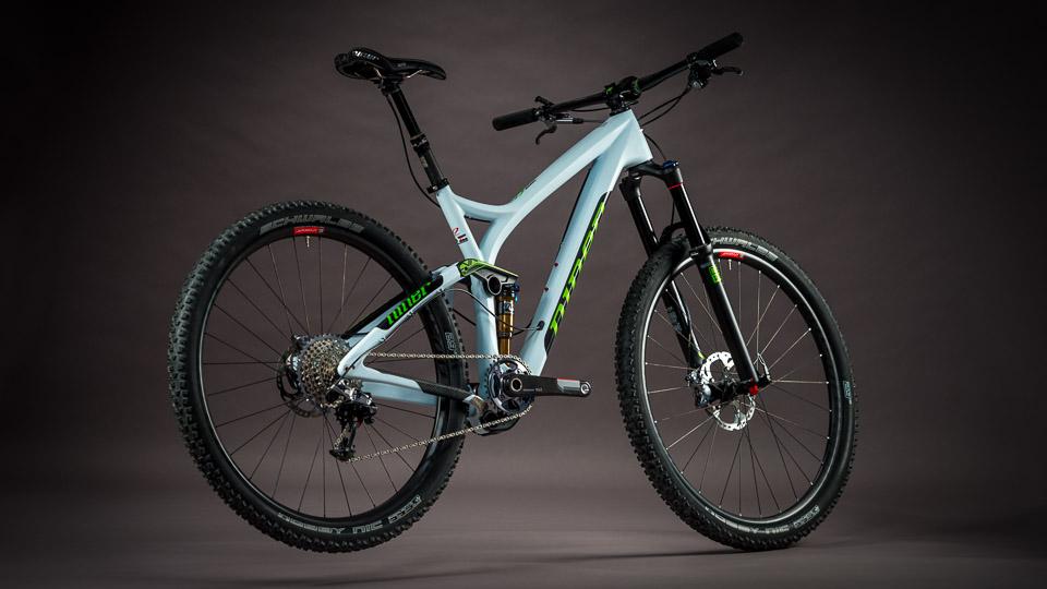Niner R.I.P. 9 RDO: A sleek, modern mountain bike with a light blue frame, black and green accents, and rugged tires. The bike features a front suspension fork, a rear shock, and a multi-gear gearbox, positioned against a dark backdrop.