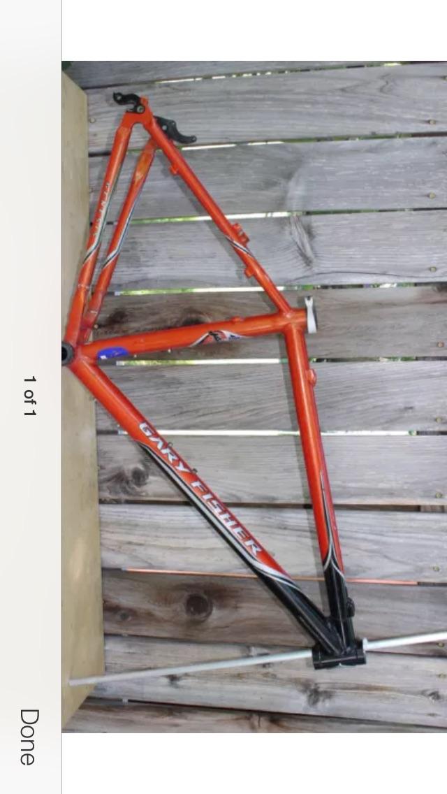 Gary Fisher Big Sur: An orange bicycle frame with black and white accents resting on a wooden surface. The frame features the text "Gary Fisher" along its side.