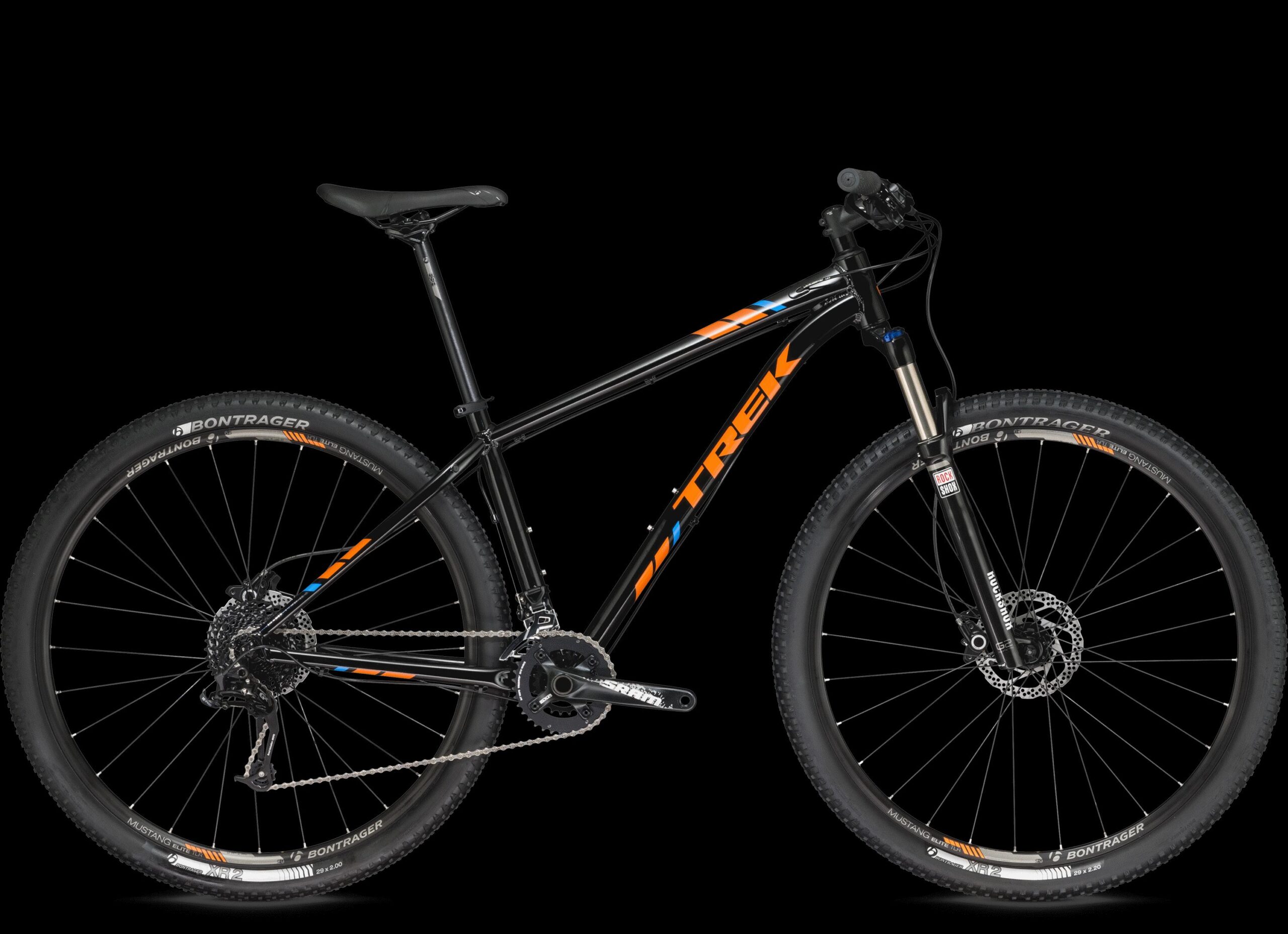 Trek X-Caliber 8: A black mountain bike with orange and blue accents, featuring wide tires, disc brakes, and a front suspension fork. The bike is positioned against a black background, showcasing its design and components.