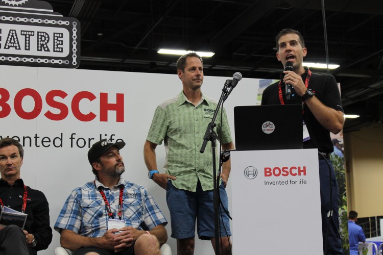 A panel discussion featuring four speakers at a Bosch event, with one speaker presenting at a microphone while others listen. The backdrop includes the Bosch logo and the phrase "Invented for life." The setting appears to be a conference or exhibition hall.
