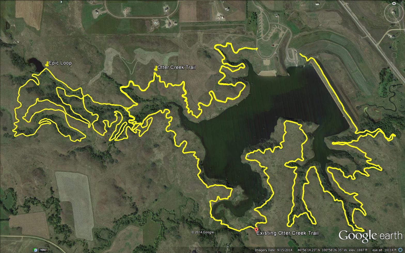Aerial view of a landscape with several winding trails marked in yellow, showing the layout of the Epic Loop, Otter Creek Trail, and Existing Otter Creek Trail near a body of water. The image features a mix of natural terrain and agricultural land. Harmon mountain bike trail.